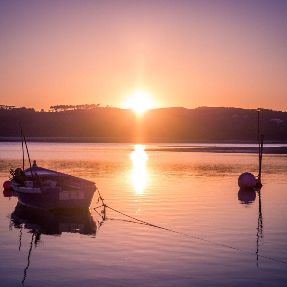 An old fishing boat at the river with the breathtaking view of the sunset in the background